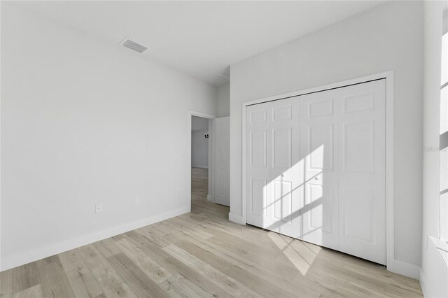 unfurnished bedroom featuring baseboards, visible vents, wood finished floors, and a closet