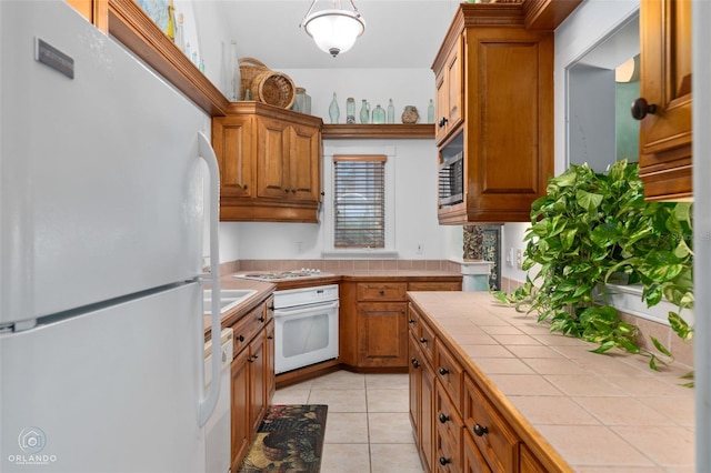 kitchen with stainless steel appliances, tile countertops, and light tile patterned floors