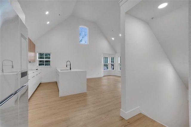 kitchen featuring a sink, light countertops, light wood-style flooring, high vaulted ceiling, and modern cabinets