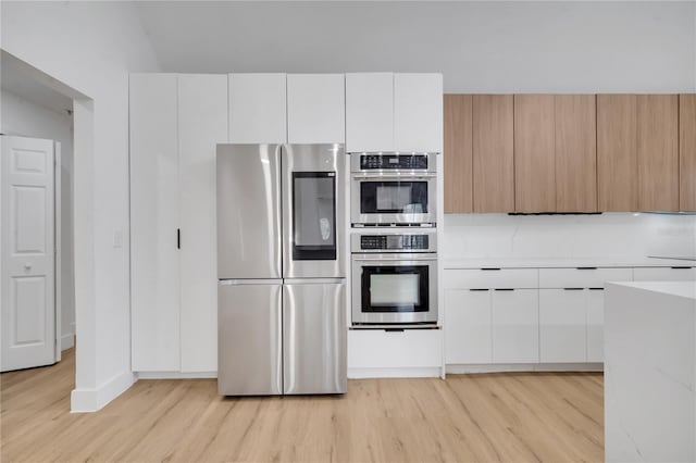 kitchen with light wood finished floors, stainless steel appliances, light countertops, white cabinets, and modern cabinets