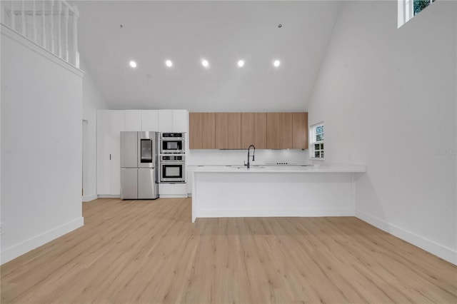 kitchen with appliances with stainless steel finishes, light countertops, a peninsula, and a sink