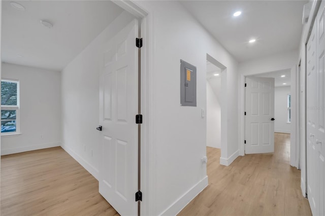 corridor featuring light wood-style flooring, electric panel, recessed lighting, and baseboards