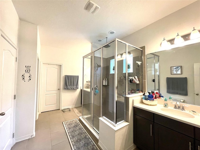 bathroom with tile patterned flooring, vanity, a shower with shower door, and a textured ceiling