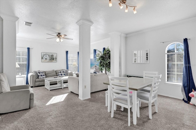 dining area featuring ornamental molding, light colored carpet, a textured ceiling, and ornate columns