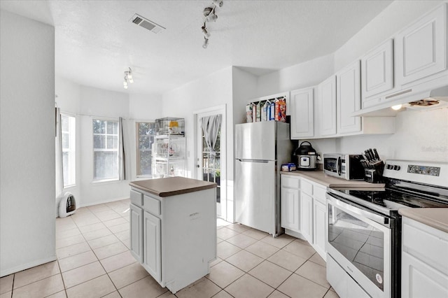 kitchen featuring stainless steel appliances, light tile patterned floors, and white cabinets