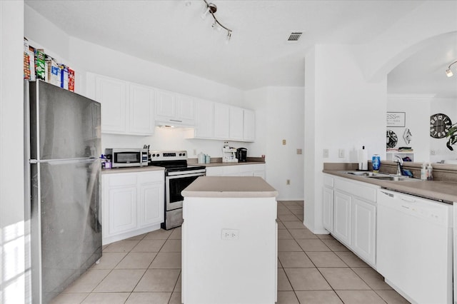 kitchen featuring light tile patterned flooring, appliances with stainless steel finishes, sink, white cabinets, and a center island