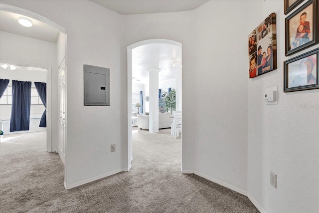 hallway with ornate columns, light carpet, and electric panel