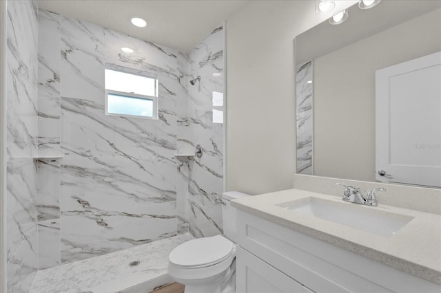 bathroom featuring a tile shower, vanity, and toilet