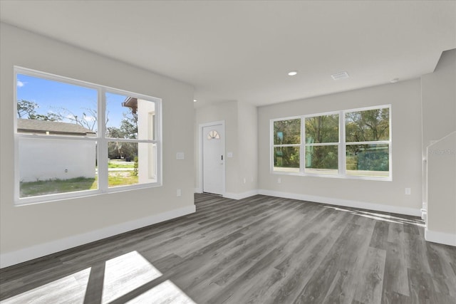 unfurnished living room with dark wood-type flooring and a wealth of natural light