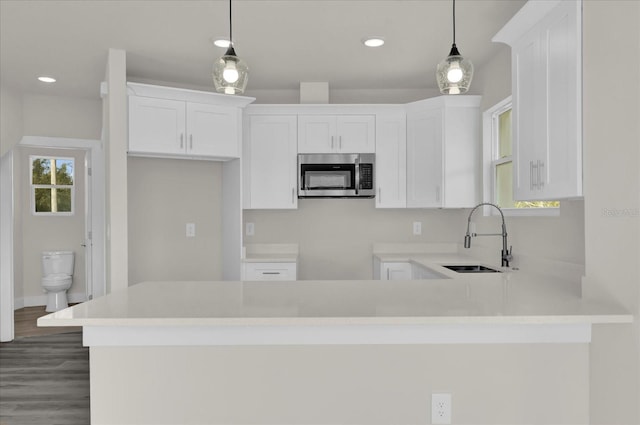 kitchen featuring sink, hanging light fixtures, white cabinetry, and kitchen peninsula