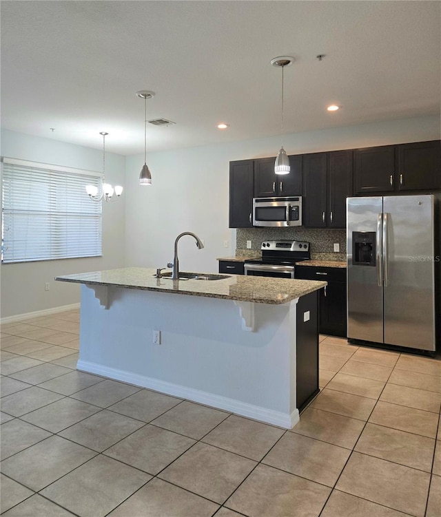 kitchen featuring appliances with stainless steel finishes, decorative light fixtures, sink, a kitchen island with sink, and light tile patterned floors