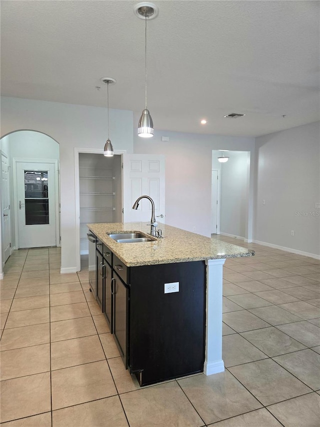 kitchen with pendant lighting, sink, an island with sink, and light tile patterned floors