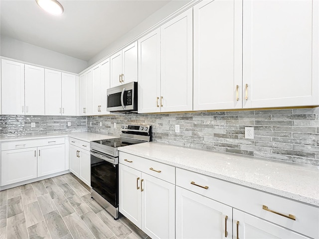 kitchen with light hardwood / wood-style flooring, appliances with stainless steel finishes, light stone counters, tasteful backsplash, and white cabinets