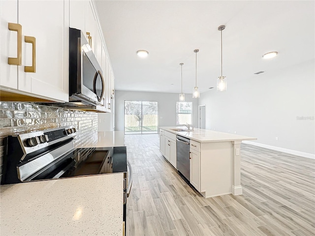 kitchen featuring decorative light fixtures, an island with sink, white cabinets, and appliances with stainless steel finishes