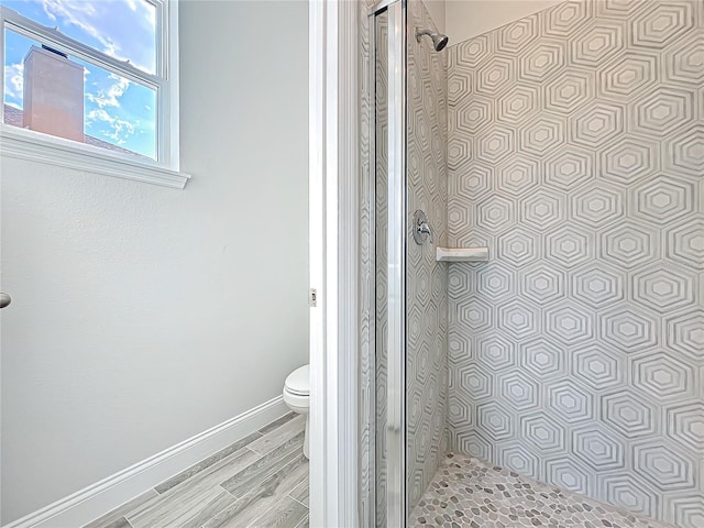 bathroom featuring toilet, a shower with shower door, and hardwood / wood-style floors