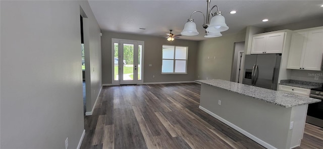 kitchen featuring appliances with stainless steel finishes, decorative light fixtures, white cabinetry, dark hardwood / wood-style flooring, and light stone countertops