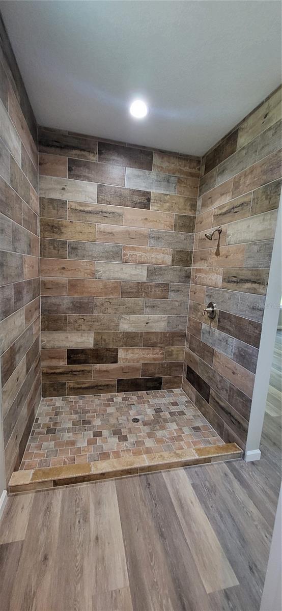 room details with a tile shower and hardwood / wood-style floors