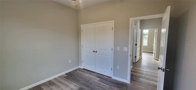 unfurnished bedroom with dark wood-type flooring and a closet