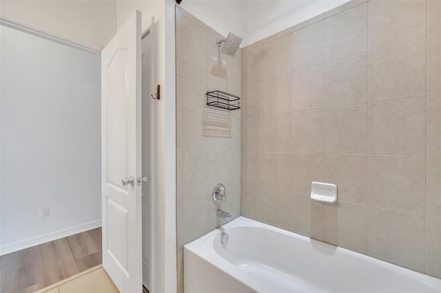 bathroom featuring wood-type flooring and tiled shower / bath