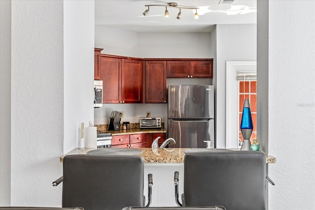 kitchen with stainless steel appliances, rail lighting, sink, and light stone counters