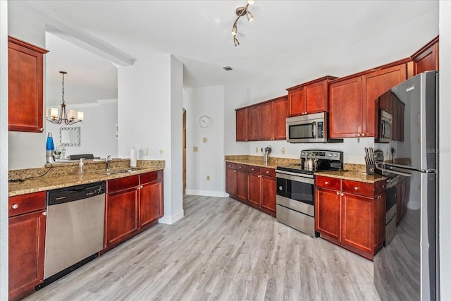 kitchen featuring pendant lighting, sink, light stone counters, stainless steel appliances, and light hardwood / wood-style flooring