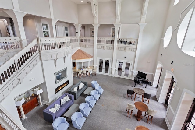 living room with carpet flooring, a towering ceiling, and ornate columns