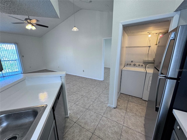 kitchen with vaulted ceiling, light tile patterned flooring, decorative light fixtures, sink, and independent washer and dryer