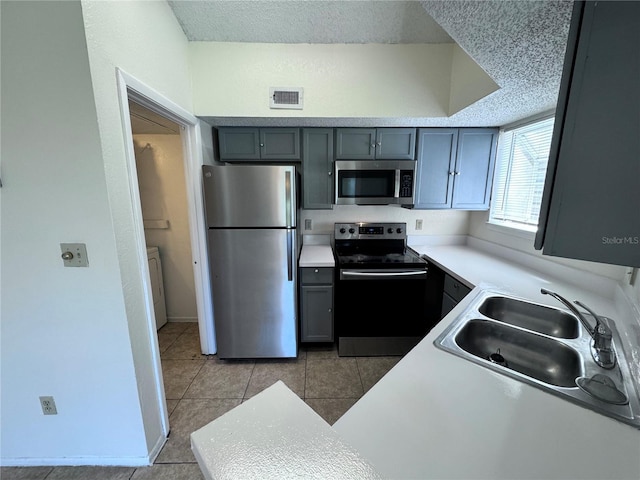 kitchen featuring sink, light tile patterned floors, gray cabinets, and stainless steel appliances