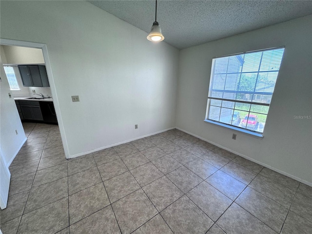 spare room with sink, light tile patterned floors, and a textured ceiling