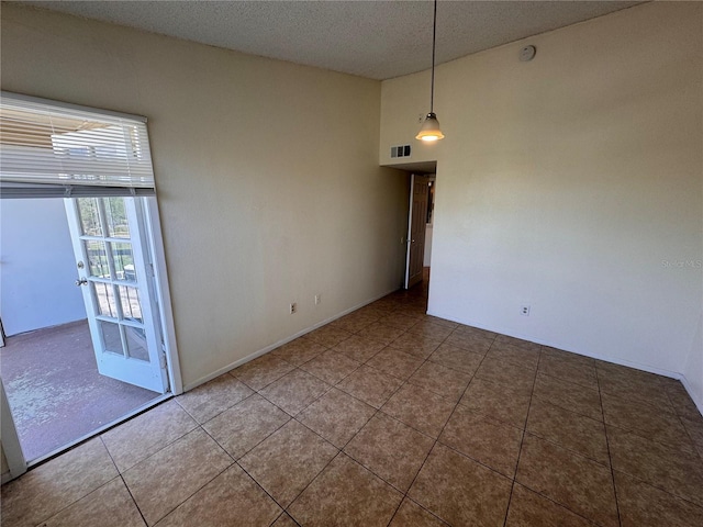 spare room with tile patterned flooring and a textured ceiling