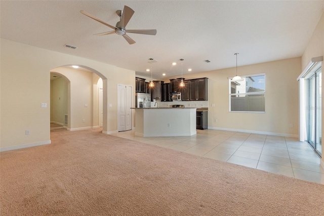 unfurnished living room with ceiling fan, light colored carpet, and a textured ceiling