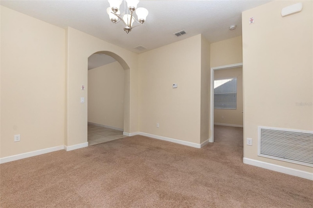 carpeted empty room with a notable chandelier