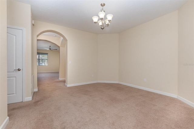 carpeted spare room featuring ceiling fan with notable chandelier