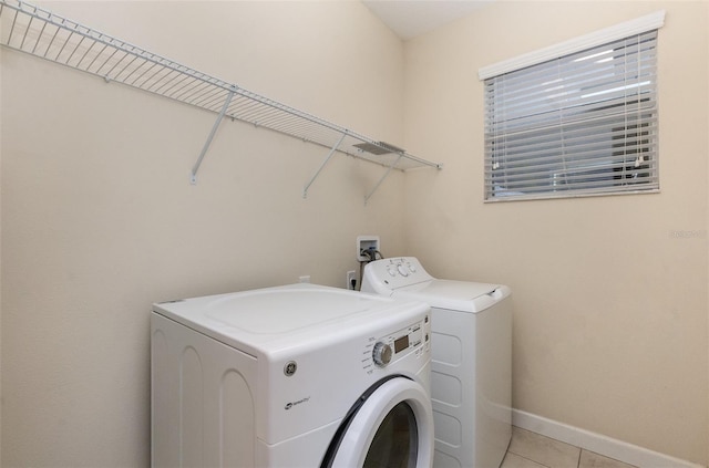 laundry area with separate washer and dryer and light tile patterned floors