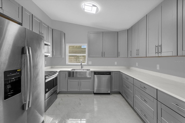 kitchen with vaulted ceiling, stainless steel appliances, sink, and gray cabinetry