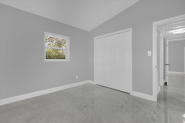 unfurnished bedroom featuring vaulted ceiling and a closet