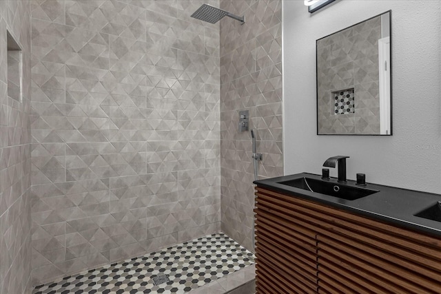 bathroom featuring tiled shower and vanity