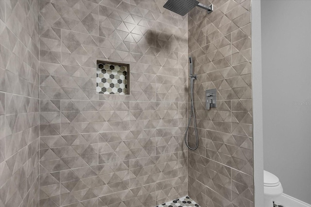 bathroom with a tile shower and toilet