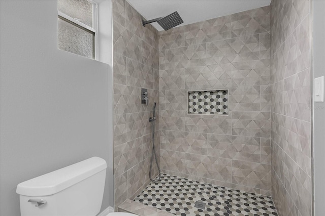 bathroom featuring a tile shower and toilet