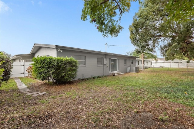 rear view of house featuring a yard and central air condition unit