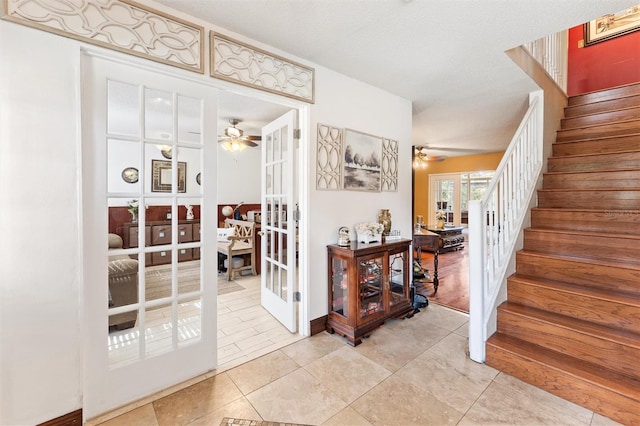 foyer entrance with light tile patterned floors, a textured ceiling, french doors, and ceiling fan