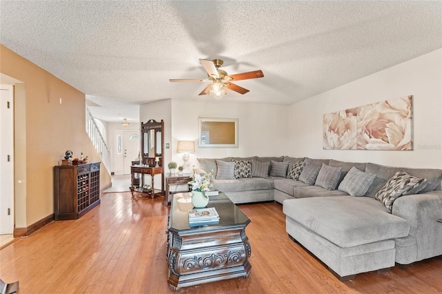 living room with ceiling fan, wood-type flooring, and a textured ceiling