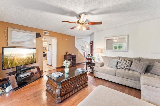 living room with ceiling fan, hardwood / wood-style floors, and a textured ceiling