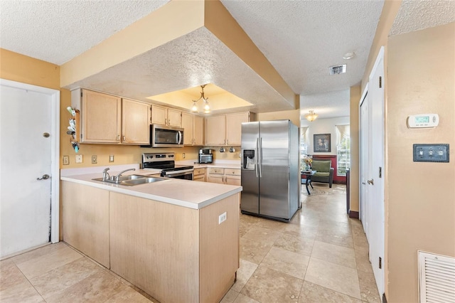 kitchen featuring appliances with stainless steel finishes, light brown cabinetry, sink, kitchen peninsula, and a raised ceiling