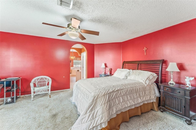 carpeted bedroom with ceiling fan, connected bathroom, and a textured ceiling