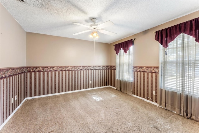 empty room with ceiling fan, carpet floors, and a textured ceiling