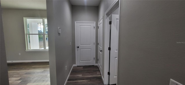 hallway with dark wood-style flooring and baseboards