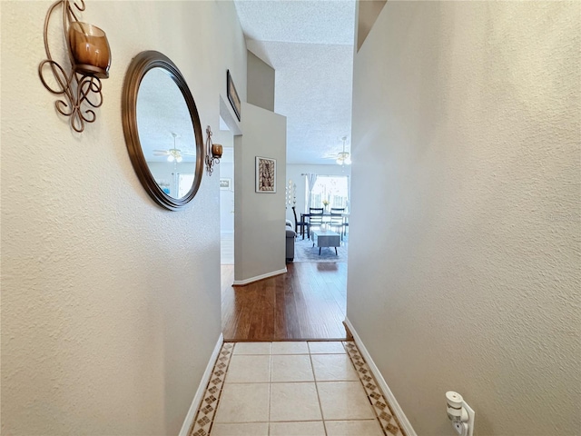 hallway with a textured ceiling and light tile patterned floors