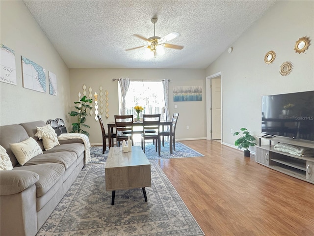 living room with lofted ceiling, a textured ceiling, wood-type flooring, and ceiling fan