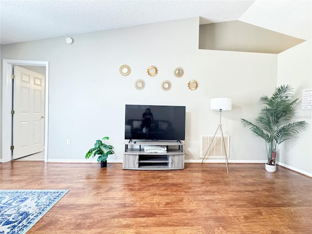 living room with vaulted ceiling, hardwood / wood-style floors, and a textured ceiling